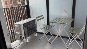 Un balcon avec une table et deux chaises, un radiateur et une vue sur les immebles.