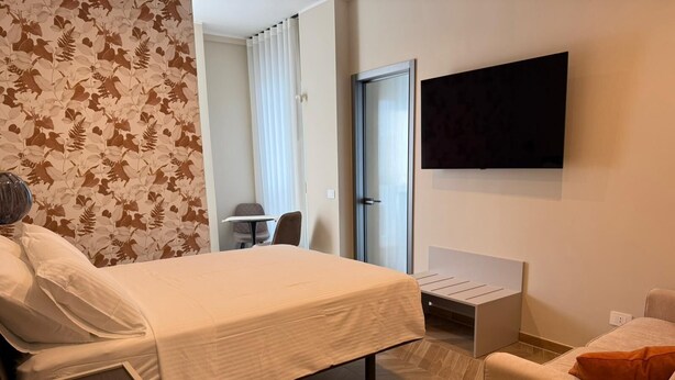 Une chambre d’hôtel avec un lit, un téléviseur fixé au mur, un bureau et une chaise.