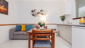 A compact living space with a dining table, wooden chairs, a sofa with cushions, a wall-mounted decorative piece, and a window with blinds. - A5 - Bright & spacious, 1 bathroom apartment! (Connolly)