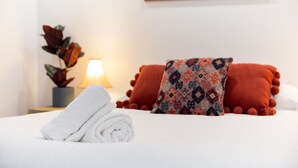 A neatly made bed with white linens, a rolled towel, and two decorative pillows with a geometric pattern. - A5 - Bright & spacious, 1 bathroom apartment! (Connolly)
