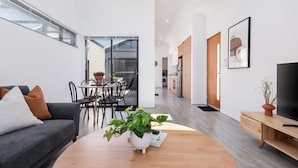 Ein stilvolles Wohnzimmer mit einer Couch, einem Couchtisch und einem Essbereich mit Stühlen und einem Tisch.