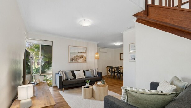 A modern living room with a sofa, coffee table, and a dining area in the background. - Seaside townhouse escape... stroll to the sea! (Scarborough)