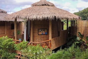 A thatched-roof hut with a wooden porch and a picture on the wall. - Nansilarom Boutique Resort (Pua)
