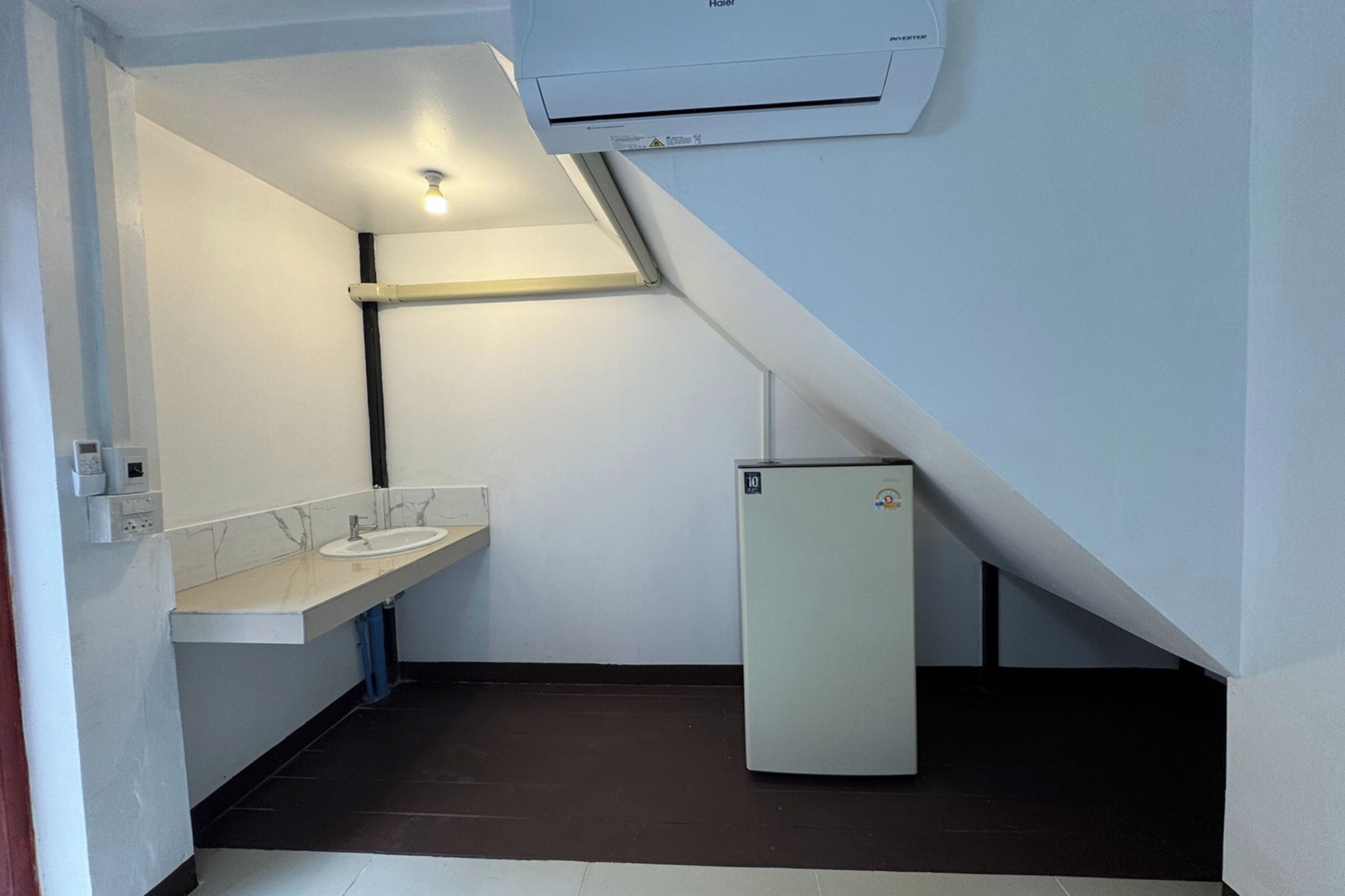 Casa de banho compacta com lavatório, espelho e pequeno frigorífico.