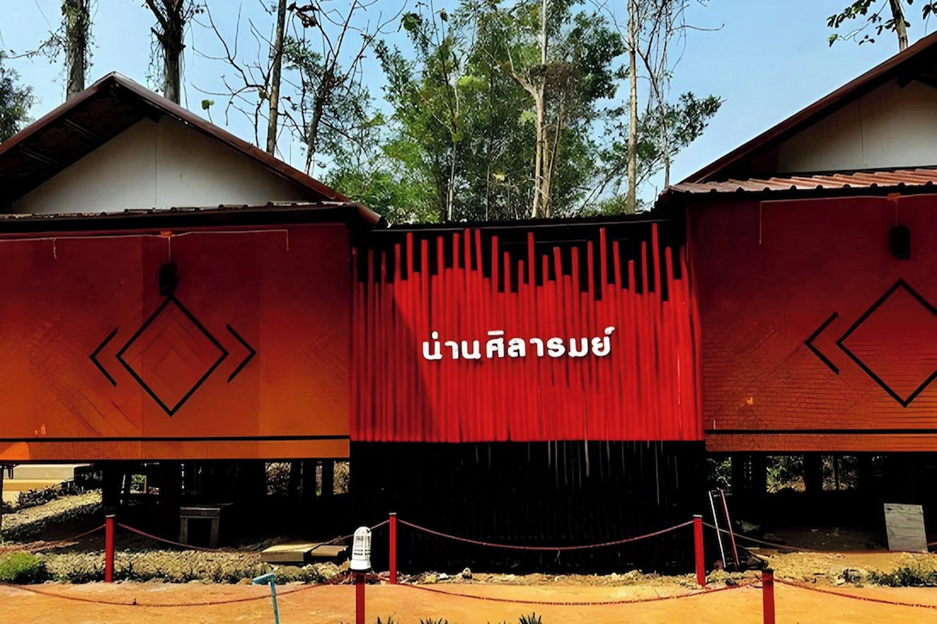 Ein Gebäude mit roter Fassade und thailändischen Schriftzeichen.