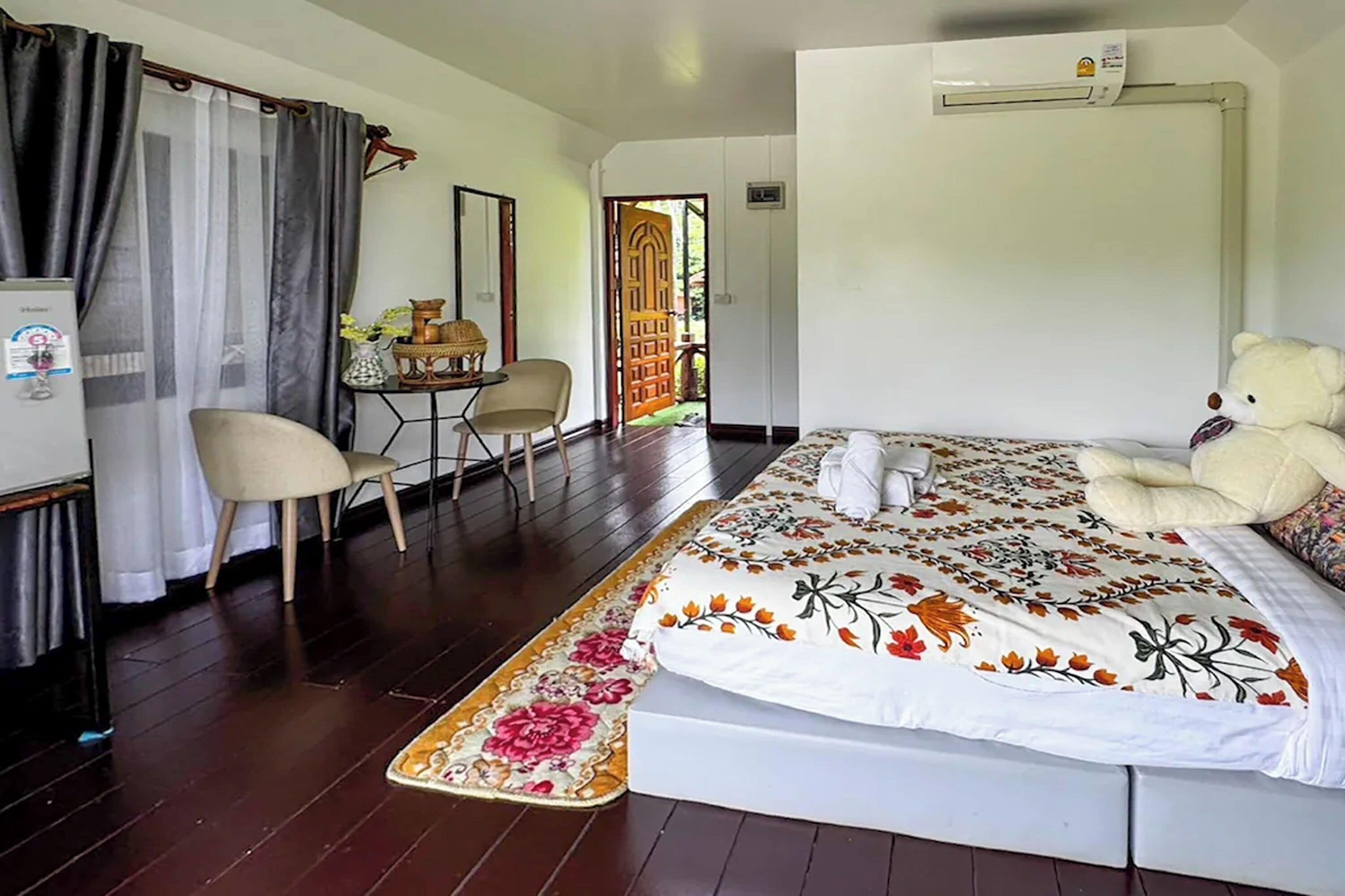A hotel room with a bed, a chair, a small table, and a window with curtains.