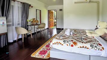 A hotel room with a bed, a chair, a small table, and a window with curtains.