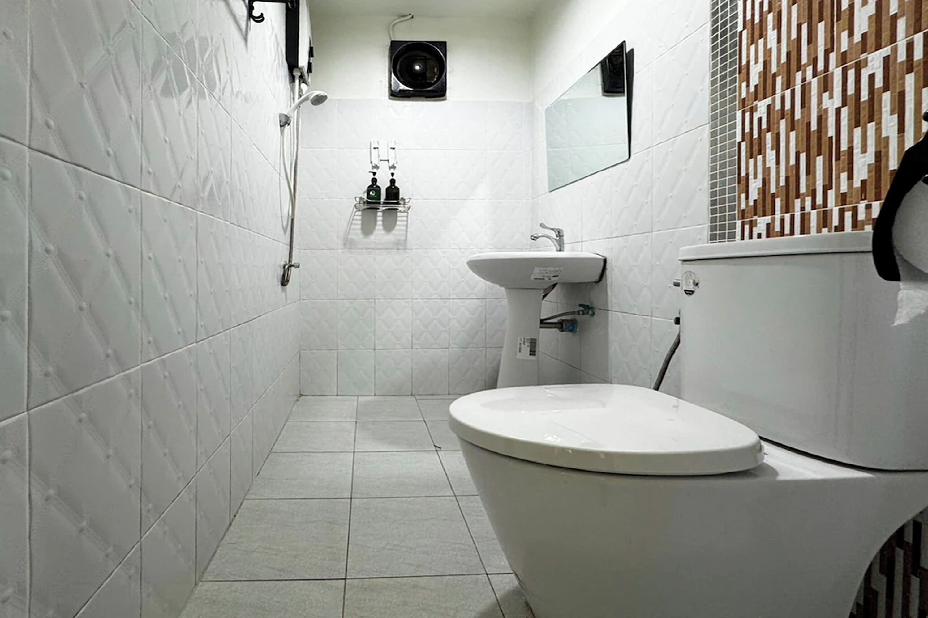 Un baño con inodoro, lavamanos y zona de ducha.