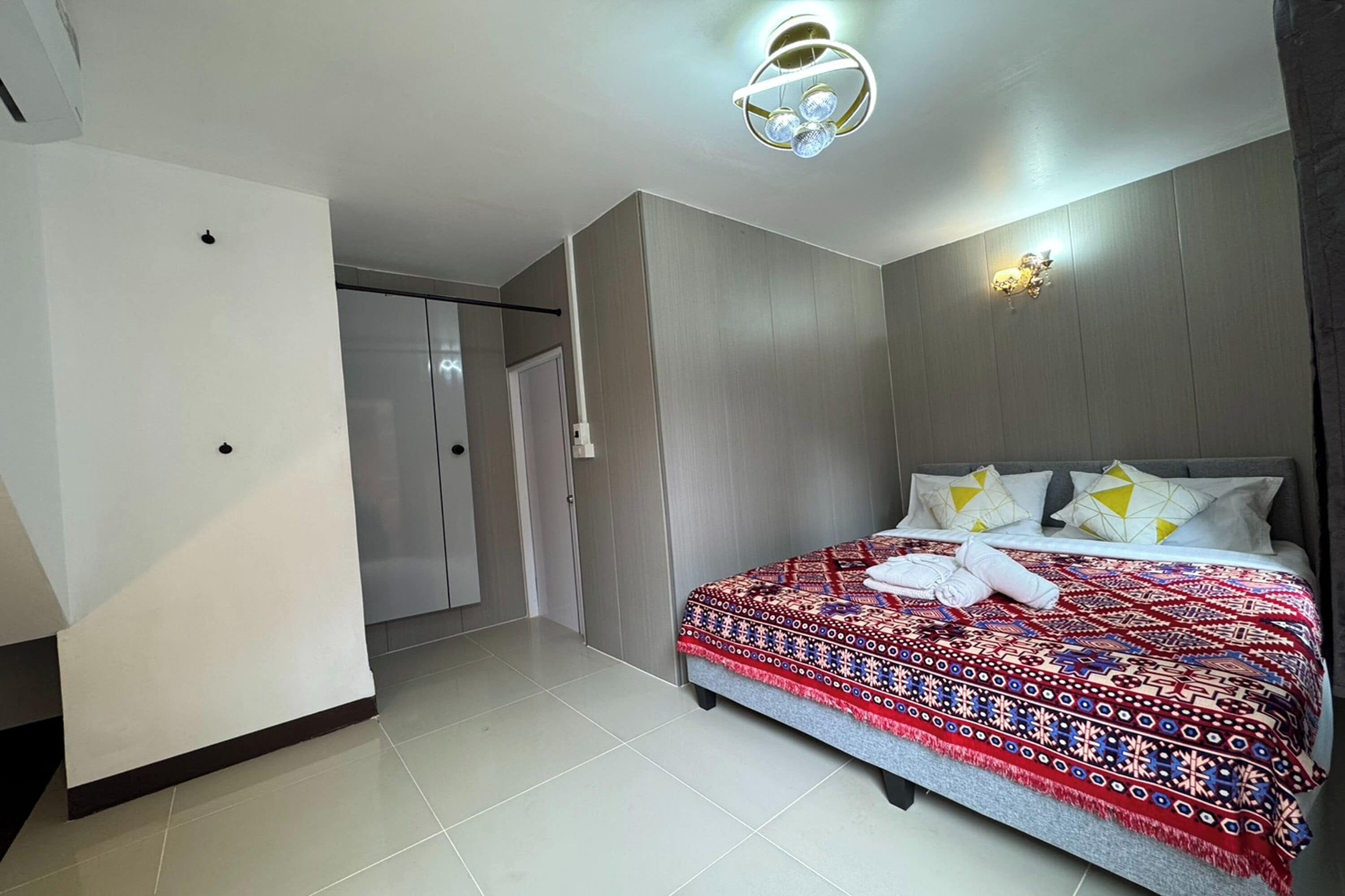 A hotel room with a bed, a wardrobe, a door, and a light fixture.