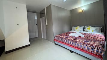 A hotel room with a bed, a wardrobe, a door, and a light fixture.