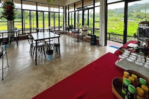 A spacious indoor area with large windows, tables, chairs, and a buffet setup. - Nansilarom Boutique Resort (Pua)