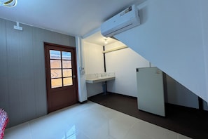 A compact hotel room with a door, a window, a sink, and a refrigerator. - Nansilarom Boutique Resort (Pua)