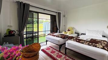 A hotel room with two beds, a large window, a view of the outdoors, and a small table with a kettle.