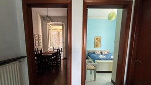 A hallway leading to a dining area with a table and chairs, and a bedroom with a bed and a nightstand. - Apartment in Chiavari (Chiavari)