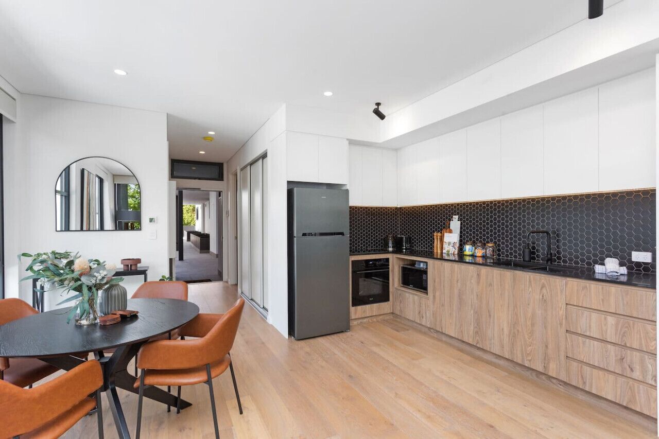 A modern kitchen with a black countertop, wooden cabinets, and a black refrigerator.