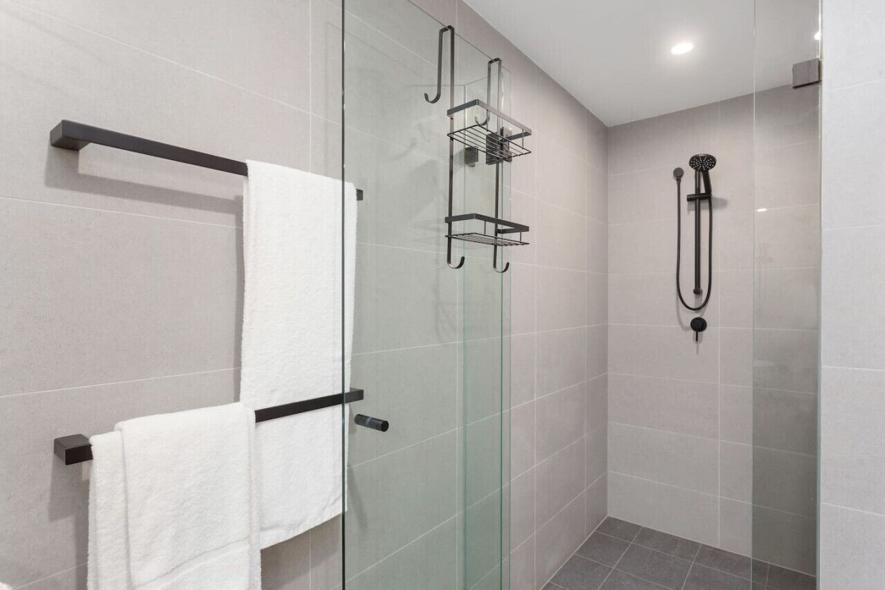 Un bagno moderno con box doccia in vetro, portasciugamani e soffione.