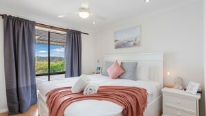 A bedroom with a bed, a nightstand, a ceiling fan, a window with curtains, and a painting on the wall. - Incredible family home in the heart of Beldon! (Beldon)