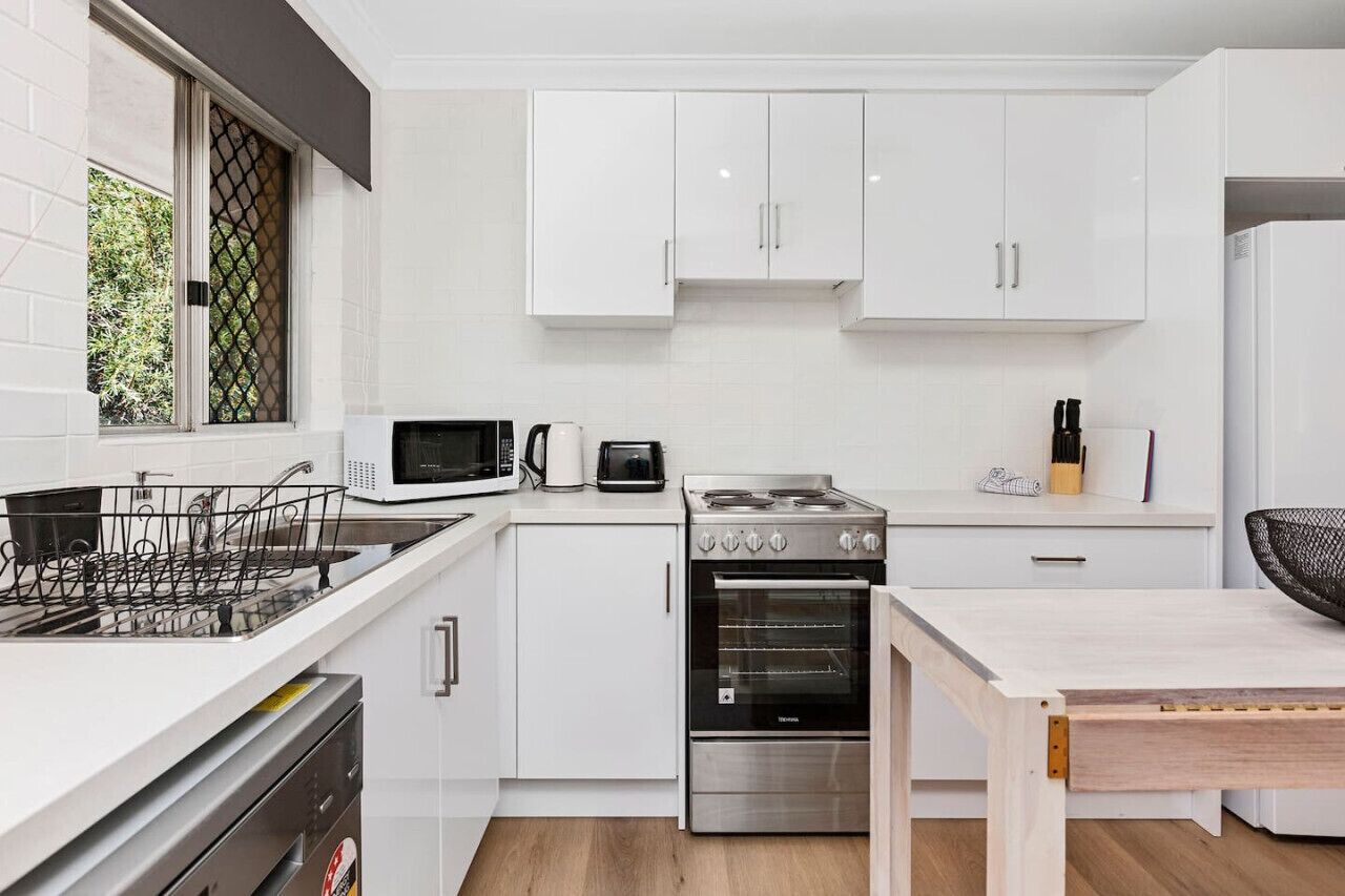 Une cuisine moderne avec des meubles blancs, un four à micro-ondes, une cuisinière et un four traditionnel.