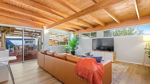 A modern living room with a wooden ceiling, a large sofa, a TV, and a view of the outdoors. - Dreamy getaway awaits for the ultimate relaxation! (Hamersley)