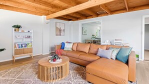 A spacious living room with a large L-shaped sofa, a round wooden coffee table, and a bookshelf. - Dreamy getaway awaits for the ultimate relaxation! (Hamersley)
