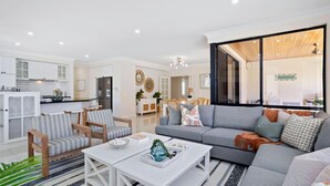 Una sala de estar moderna con un sofá gris, sillones a rayas y una mesa de centro blanca.