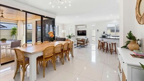 Una cocina amplia y luminosa con comedor, ventanas grandes y una moderna lámpara de araña.