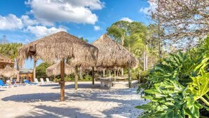 A beach area with thatched umbrellas, lounge chairs, and a sandy path. - BB614NPP - Relaxing 3BR Corner Condo • Sleeps 6 (Davenport)