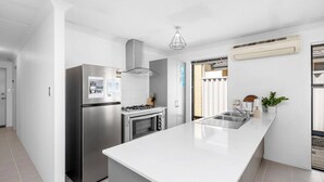 A modern kitchen with a central island, stainless steel appliances, and a built-in oven. - Jindee Beach 2km away | Magical memories in Butler (Butler)