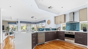 Una cocina moderna con muebles oscuros, electrodomésticos de acero inoxidable y una isla central.