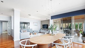 Una sala de estar moderna con una mesa de comedor de madera, sillas blancas y un sofá.