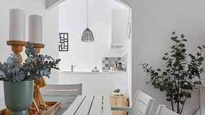 A modern dining area with a white table and chairs, a wooden sideboard, and a potted plant. - Bright & Stylish by the Sea! (Scarborough)