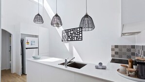 A modern kitchen with white cabinetry, a built-in sink, and pendant lighting. - Bright & Stylish by the Sea! (Scarborough)