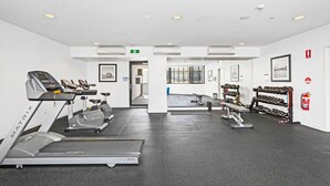 Un gimnasio con cintas de correr, bicicletas estáticas y bancos de pesas.