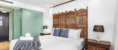 Ein Schlafzimmer mit einem großen Bett, einem Holzkopfteil, Nachttischen und einer grünen Tür.