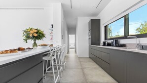Una cocina moderna con una encimera larga, taburetes de bar y un amplio ventanal.