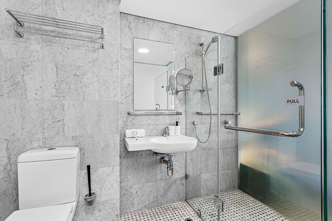 Une salle de bain moderne avec une douche à parois de verre, un lavabo blanc et des toilettes.