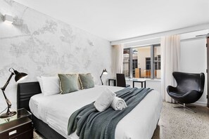 A modern hotel room with a large bed, two bedside lamps, a chair, and a view of the outside. - Nest on Newcastle – S3 (Perth)