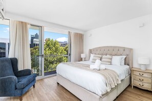 A modern bedroom with a large bed, a chair, and a nightstand.