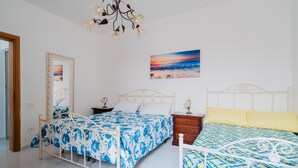 Een slaapkamer met twee bedden, een nachtkastje, een spiegel en een schilderij aan de muur.