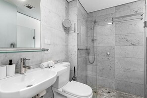 A modern bathroom with a white sink, toilet, and shower. - Nest on Newcastle – T3 (Perth)