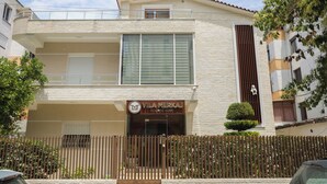 A two-story building with a balcony, a sign reading "VILA MERKAJ HOLIDAY HOME," and a wooden fence in front. - Vila Merkaj (Berat)