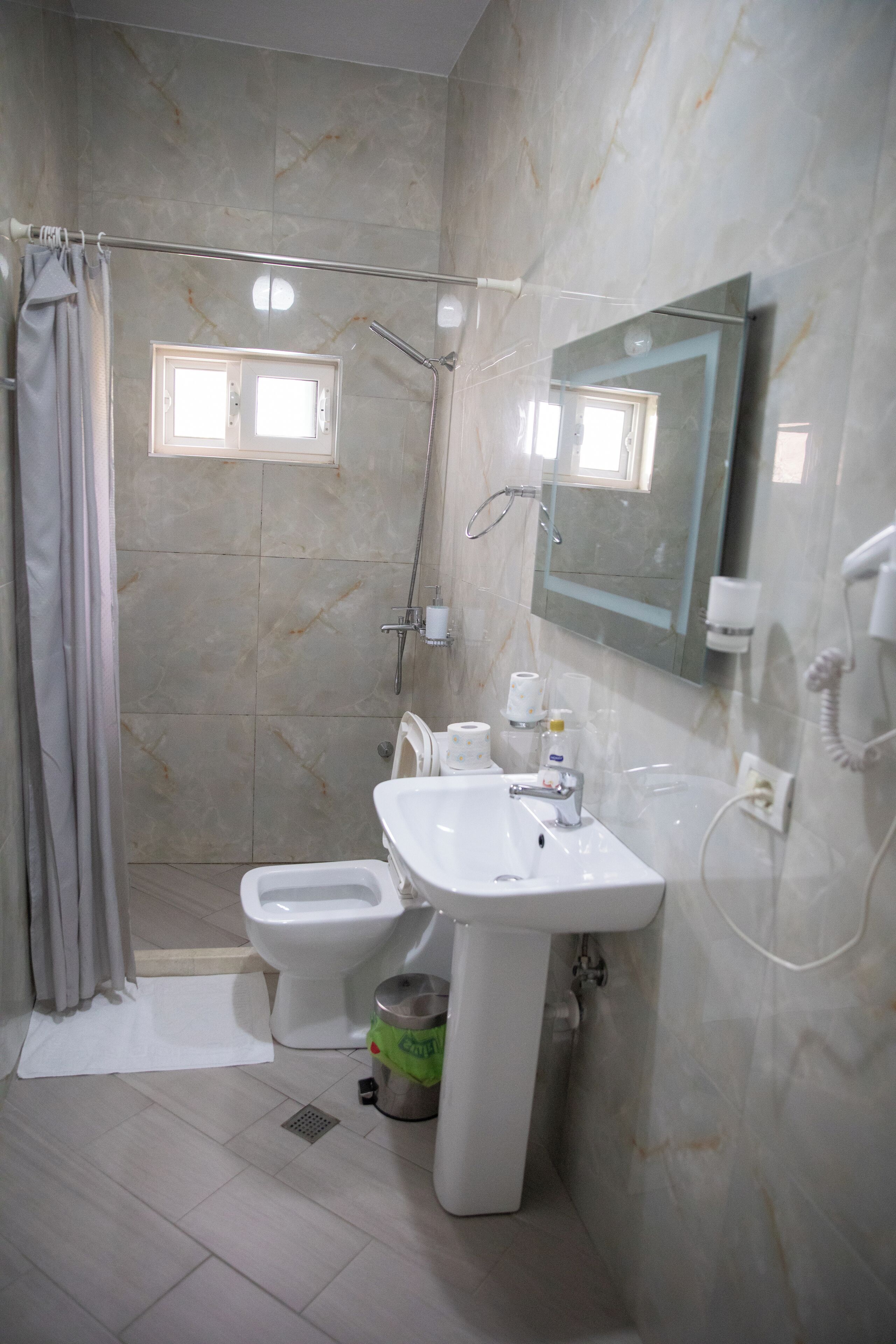 A bathroom with a shower, toilet, sink, and a mirror.