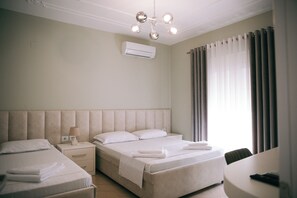 A hotel room with a large bed, a smaller bed, a bedside table with a lamp, a chair, and a desk. - Vila Merkaj (Berat)