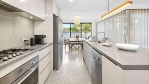 Een moderne keuken met een gasfornuis, een koffieapparaat en een groot kookeiland met een spoelbak.