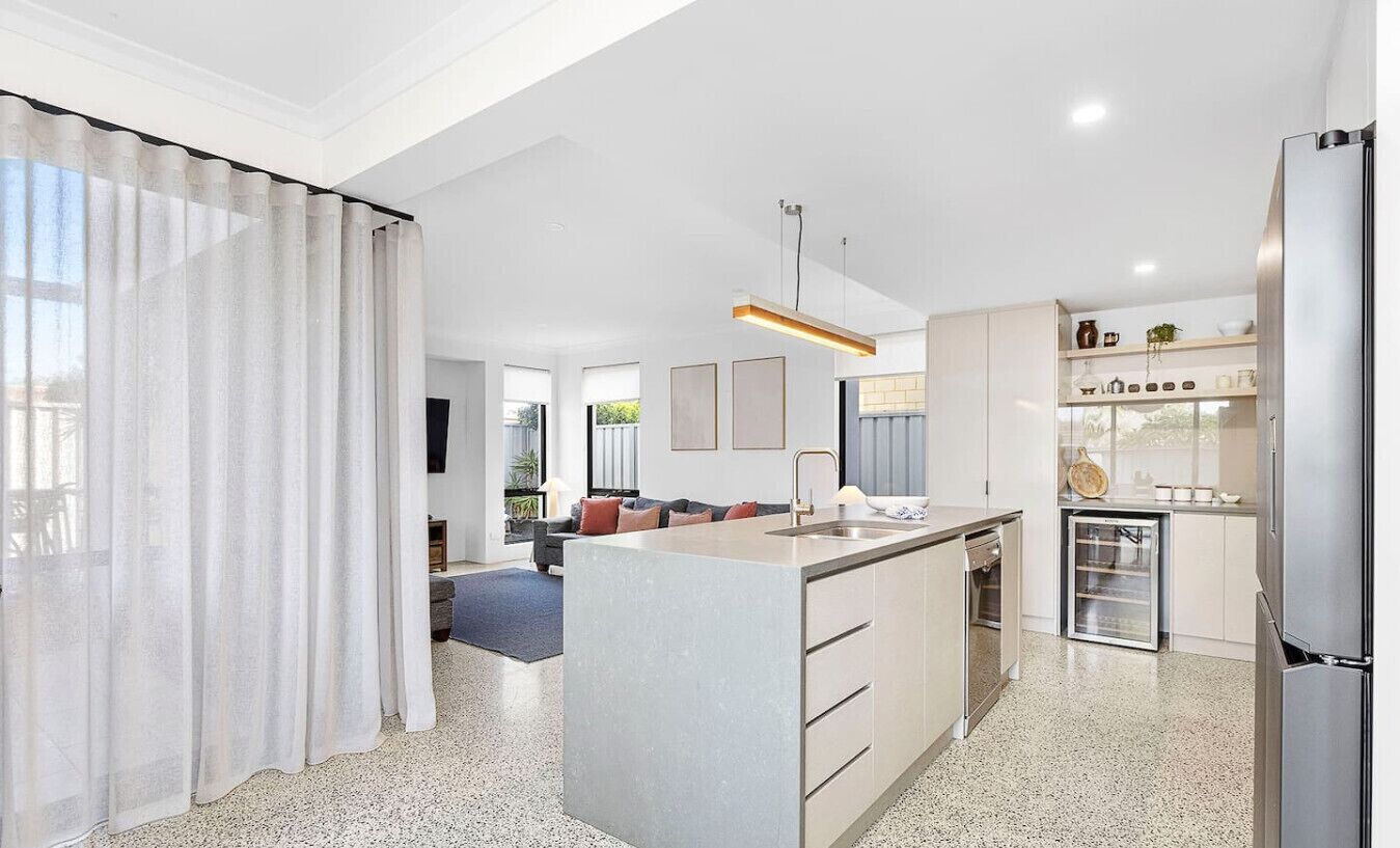 A modern kitchen with a central island, built-in appliances, and a dining area with a sofa and coffee table.