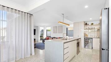 A modern kitchen with a central island, built-in appliances, and a dining area with a sofa and coffee table.