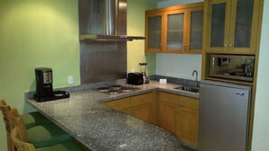 A kitchen with granite countertops, wooden cabinets, stainless steel appliances, and a coffee maker. - Cozy 1-bedroom Suite with fitness room, AC in charming Nuevo Vallarta (Nuevo Vallarta)