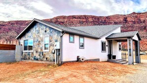 A two-story house with a stone facade, a garage, and a covered porch. - MtnViews–Hot tub-Mini Golf–Bocce–Pool Table–3000sf (Moab)