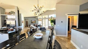 A spacious kitchen with a dining area, a large island, and a modern chandelier. - MtnViews–Hot tub-Mini Golf–Bocce–Pool Table–3000sf (Moab)
