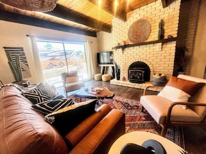 A cozy living room with a brick fireplace, leather sofa, and a comfortable chair. - NEW! MiniGolf–PoolTable–FirePit–BBQ–Arcade–Bocce (Page)